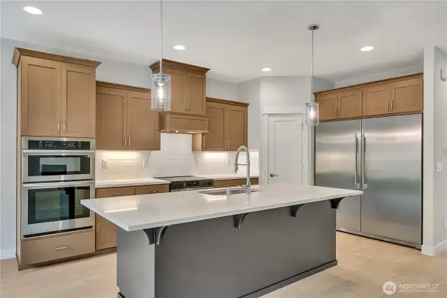 Stainless steel appliances including a deluxe refrigerator/freezer and double ovens.