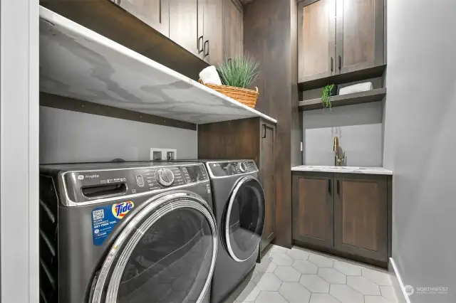 Main floor laundry room with sink and floor to ceiling cabinets.