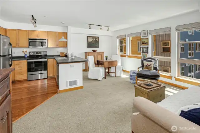 Another perspective from the spacious living room showcases the dining area and kitchen, all bathed in natural light from expansive southern windows.