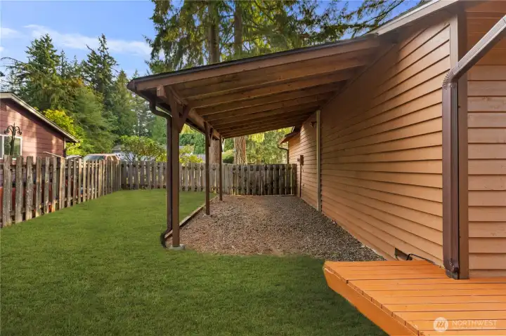 Covered space along the side of the garage in the side yard.