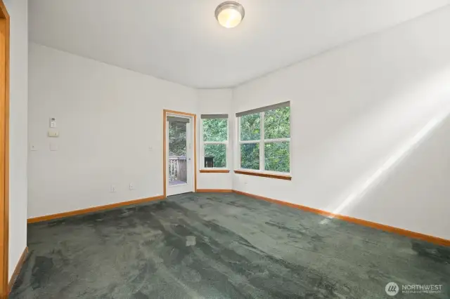 Looking across the primary bedroom toward the door leading to the private deck.