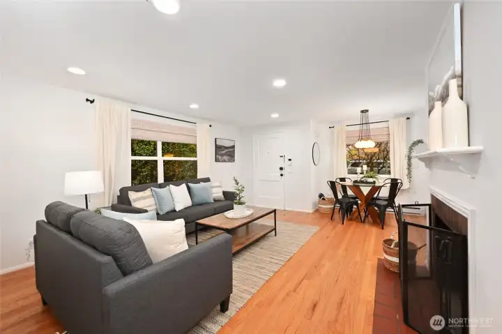 Living room with wood burning fireplace, hardwoods, updated lighting and windows.