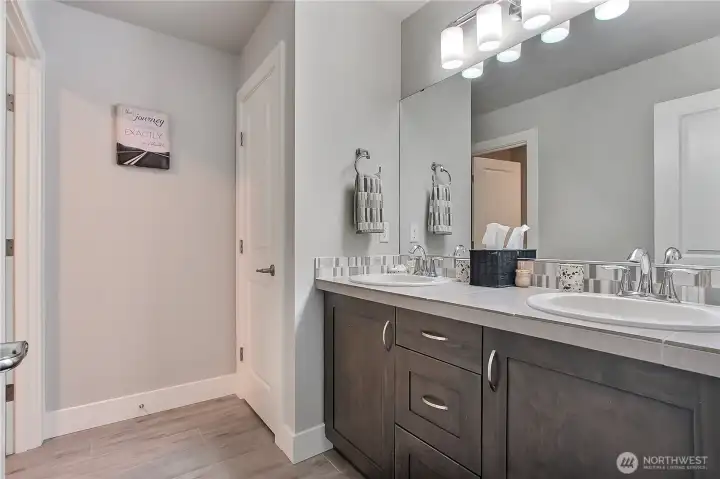 The hall bath is thoughtfully designed for convenience and privacy, with the large double-sink vanity and utility closet separated from the shower and tub area, creating a functional layout that keeps morning routines smooth and stress-free.