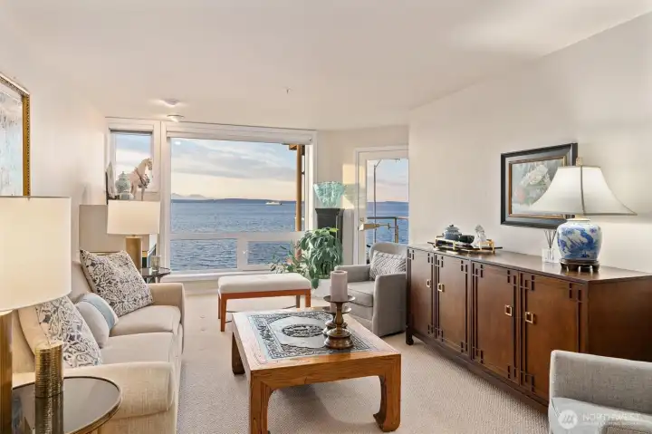 The living room is an ideal spot to watch ferries and cruise ships glide by, combining ever-changing views with cozy comfort. It features a gas fireplace for added warmth and ambiance, along with newer carpet that gives the space a fresh, inviting feel.