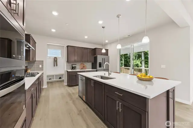 Large kitchen island with built in oven and microwave, soft close cabinets, and quartz countertops all standard. Photo of actual home with virtual staging.
