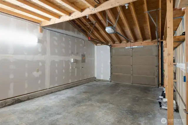 Spacious garage with loft storage and laundry hookupss near door into house.