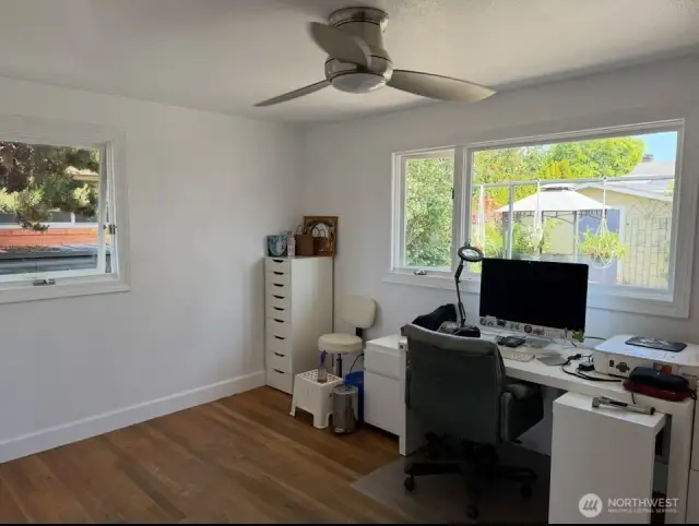 Large 2nd bedroom/office on main level newly painted with hardwood flooring ceiling fan and large windows to view yard and nature settings