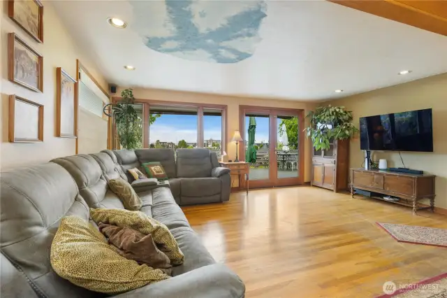 Open-concept living room with french doors lots of large windows facing the views,hardwood flooring with light and bright colors greet you in the happy home