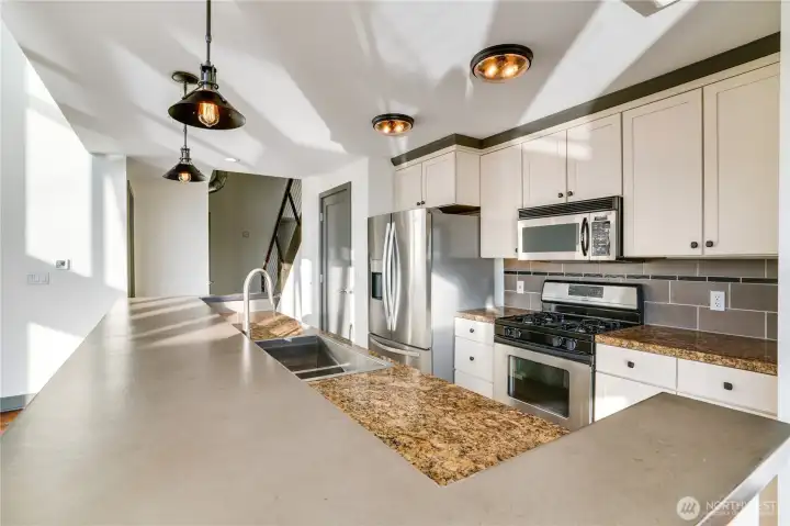 Kitchen has been tastefully upgraded with concrete countertops, modern light fixtures and large pantry to the left of the refrigerator