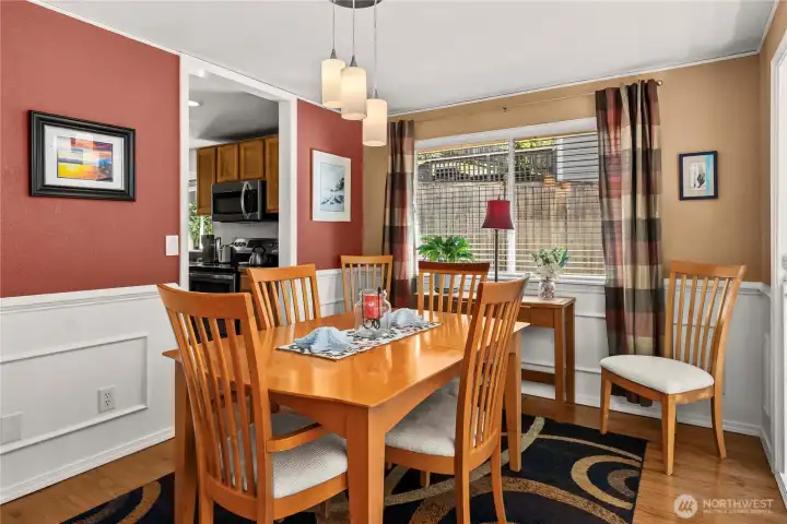 Formal dining room with hardwood floors, wainscoating, and updated light fixtures