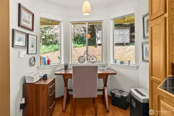 The breakfast nook is currently used as a personal office, with bay windows and a view of the backyard.