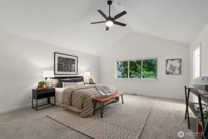 Primary bedroom with vaulted ceiling and fan.