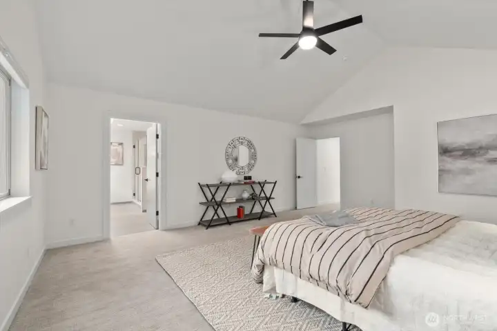 Oversized primary suite with vaulted ceilings, all window, coverings included, and ceiling fan