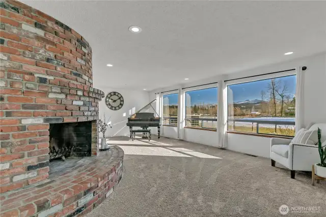 Large living room is anchored by an impressive curved brick fireplace, perfect for cozy evenings or a cold winter day.