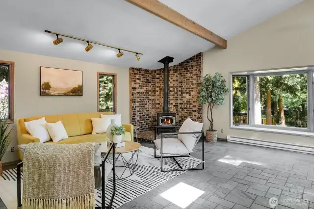 Spacious family room with vaulted ceilings, wood stove, and peaceful views of the backyard.