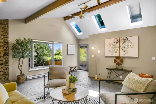 Skylights, vaulted ceiling, bay window, ceiling fan, and backyard access make this room bright and inviting.