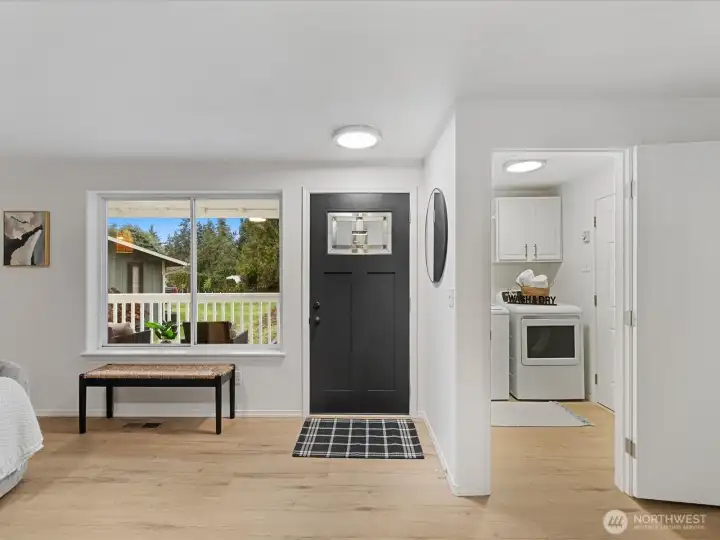 Bright entryway with modern front door, large picture window, and convenient access to the laundry room and garage