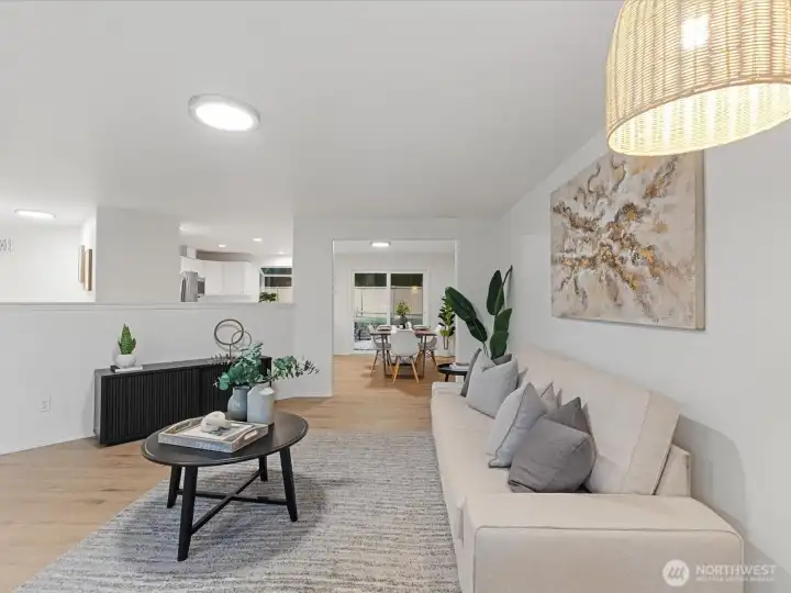 Light-filled living room with open sightlines to the dining area, kitchen and backyard