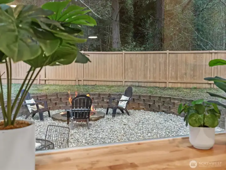 Widow view of backyard from kitchen featuring fully fenced private backyard with cozy firepit area