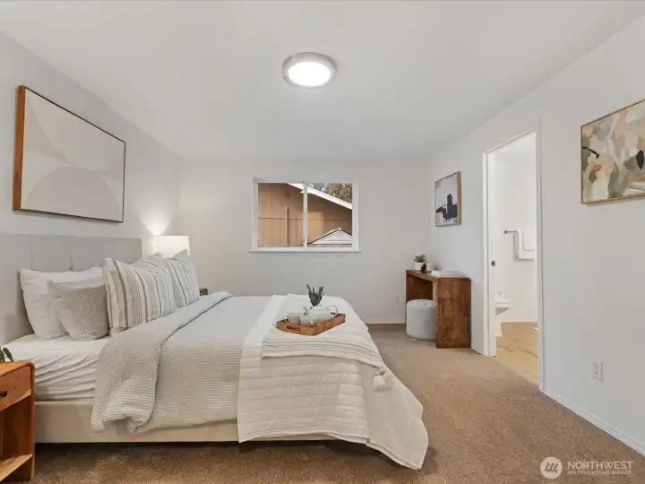 Spacious primary bedroom featuring plush new carpet, ample natural light, and private access to the ensuite bathroom