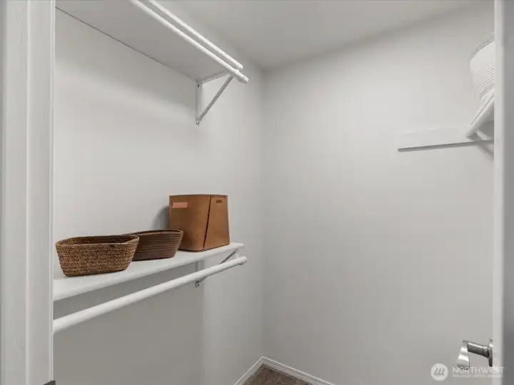 Walk-in primary closet with built-in hanging space for organized storage