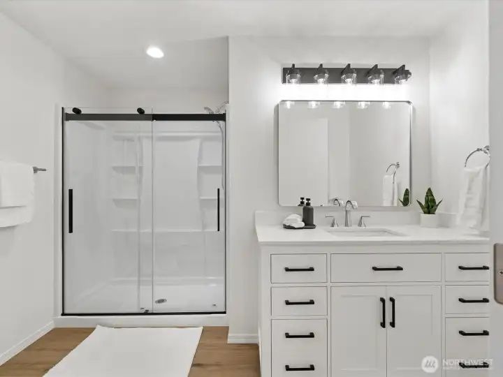 Completely remodeled primary bathroom with modern vanity and fixtures, large shower and continued LVP flooring