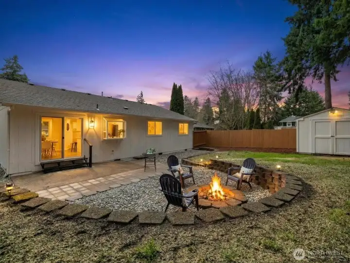 Inviting backyard at dush featuring a spacious new patio, built-in firepit seating area, and fully fenced yard of the kitchen and dining room