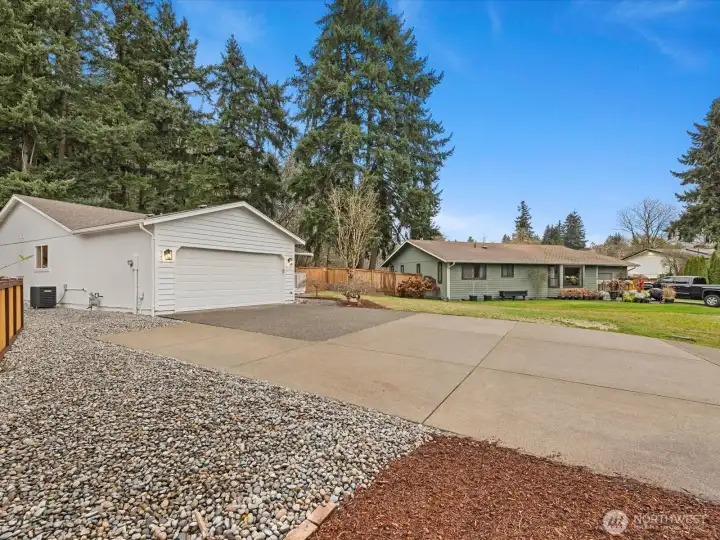 Spacious driveway and two-car garage with low-maintenance gravel landscaping and extra RV or car parking
