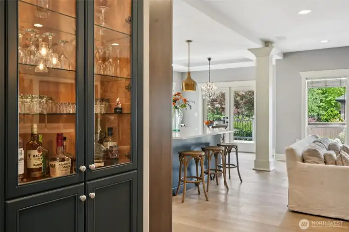 Thoughtfully designed kitchen area featuring a built-in wet bar with glass-front cabinetry, ideal for entertaining and everyday convenience. Positioned between the kitchen and living space, this feature enhances functionality while maintaining a seamless open-concept flow.