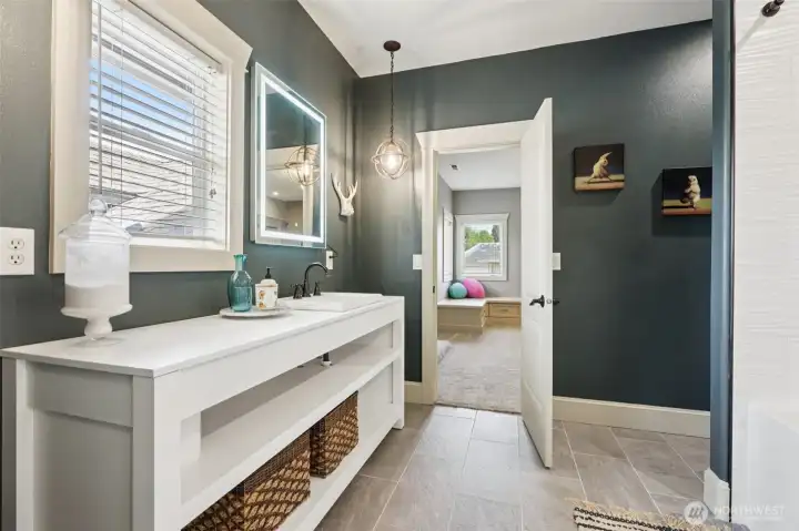 Stylishly updated bathroom featuring a modern open vanity, contemporary lighting, and sleek finishes. The space offers a clean, functional layout with natural light and thoughtful design details, conveniently located near adjacent bedrooms.