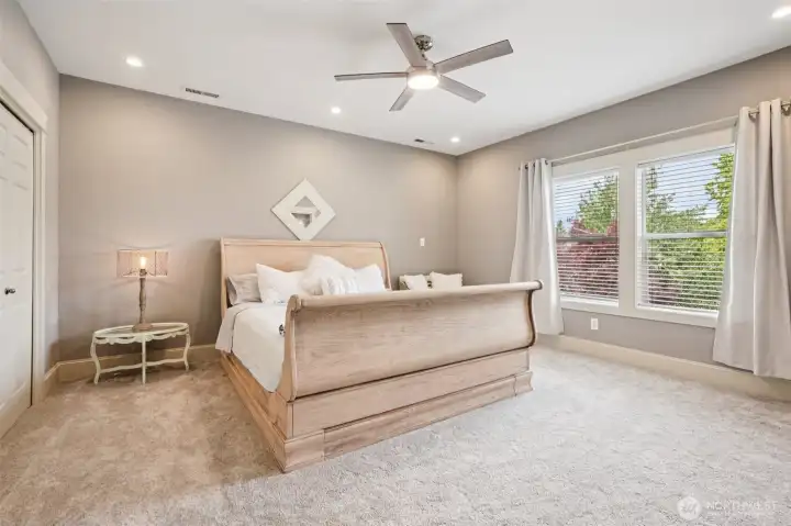 Spacious primary bedroom offering plush carpeting, recessed lighting, and a ceiling fan for year-round comfort. Large windows provide abundant natural light and peaceful views, creating a calm and inviting retreat with ample room for furnishings.