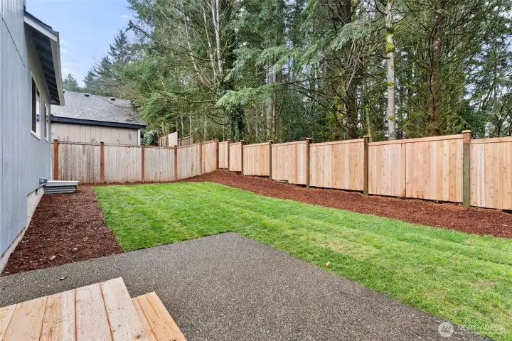 Backyard patio and wood line offers year-round use and some privacy.
