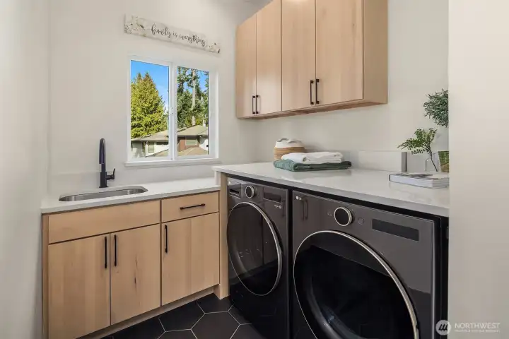 Spacious, main-level laundry room with utility sink and full size washer/dryer