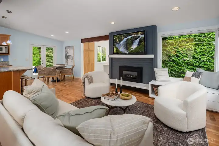 A dramatic floor-to-ceiling fireplace wall serves as the stunning focal point of this inviting living room, seamlessly connecting to the dining and kitchen areas for effortless everyday living and entertaining.