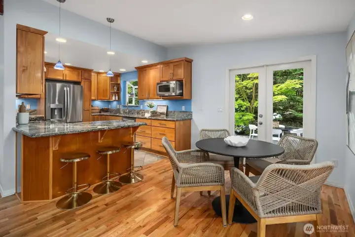 The chef's kitchen features warm custom cabinetry, granite counters, and stainless steel appliances, flowing naturally into a sun-filled casual dining area, a perfect combination for both everyday meals and effortless entertaining.