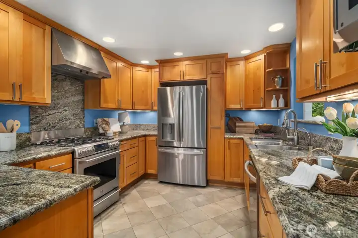 Every detail shines in this beautifully appointed kitchen, featuring granite counters, custom tile backsplash, premium stainless steel appliances, and rich warm cabinetry offering exceptional storage and style in every corner.