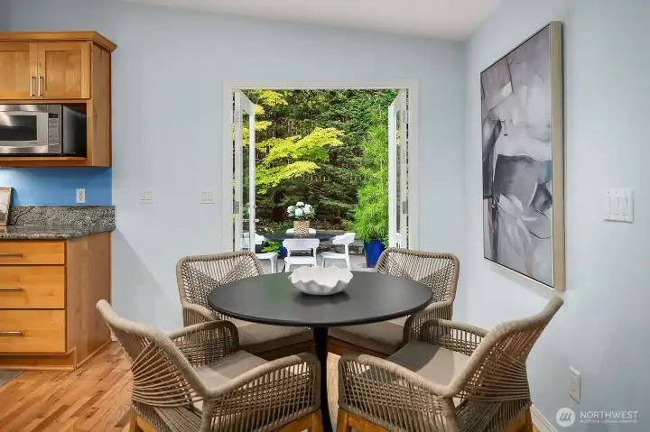 This cozy dining nook offers a peaceful garden-framed window view, creating a serene and private setting for morning coffee or casual meals surrounded by the beauty of the mature landscaping outside.