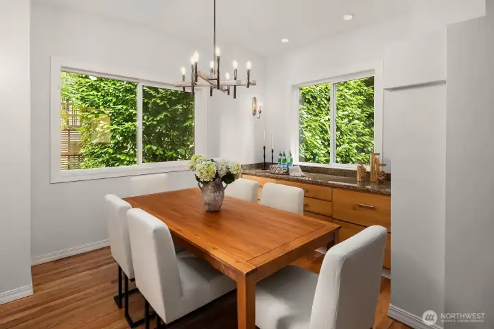 Bathed in natural light from oversized windows framing the mature greenery beyond, this inviting dining room offers a warm and stylish setting for both everyday meals and special entertaining.