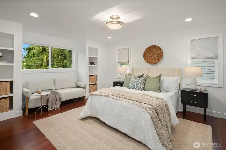 The spacious main-level primary suite offers a peaceful retreat with rich hardwood floors, large windows overlooking the mature landscaping, and generous proportions, providing comfort and privacy all on one convenient level.