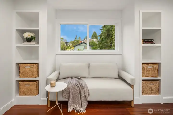 A charming built-in window seat flanked by custom shelving creates a cozy reading nook within the primary suite, a thoughtful detail that adds both warmth and functional storage to this private retreat.