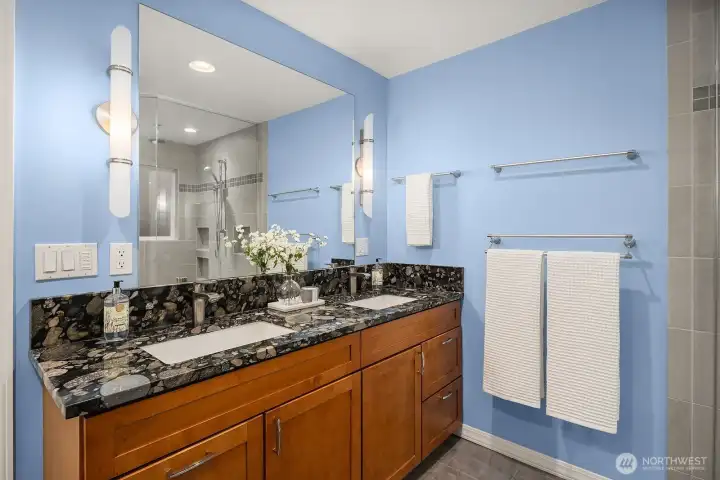 The beautifully appointed primary bath features an expansive dual vanity with granite counters, a large mirror, and an oversized dual-head shower, delivering a spa-like experience right at home.