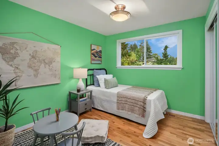 A cheerful and bright lower level bedroom with hardwood floors and dual windows offers a comfortable and private space for guests or family, ready to personalize and make your own.