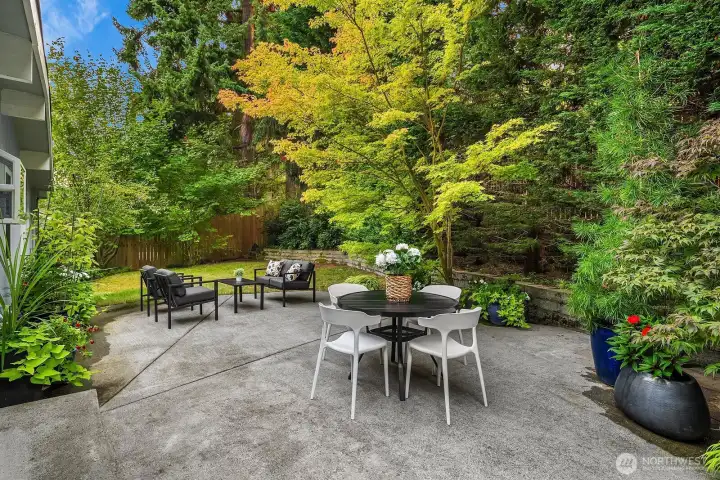 The expansive patio is surrounded by lush mature landscaping and towering trees, creating a beautifully private and serene outdoor retreat, perfect for al fresco dining, entertaining, or simply unwinding in nature.