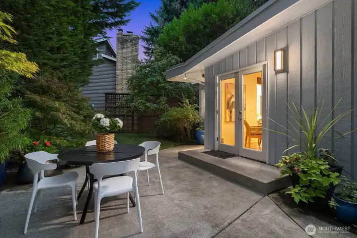 A stunning evening setting highlights the seamless indoor-outdoor connection, with elegant French doors opening to the private patio, a beautifully landscaped and intimate space perfect for entertaining under the stars.