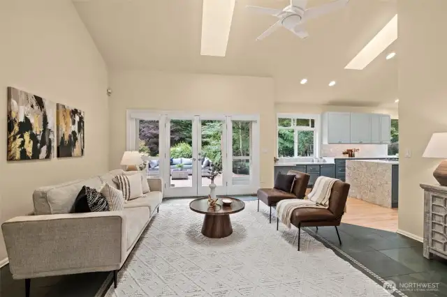 Family room off the kitchen with slate floors, gas fireplace, vaulted ceilings, skylight and French doors open to the backyard deck and large level backyard.