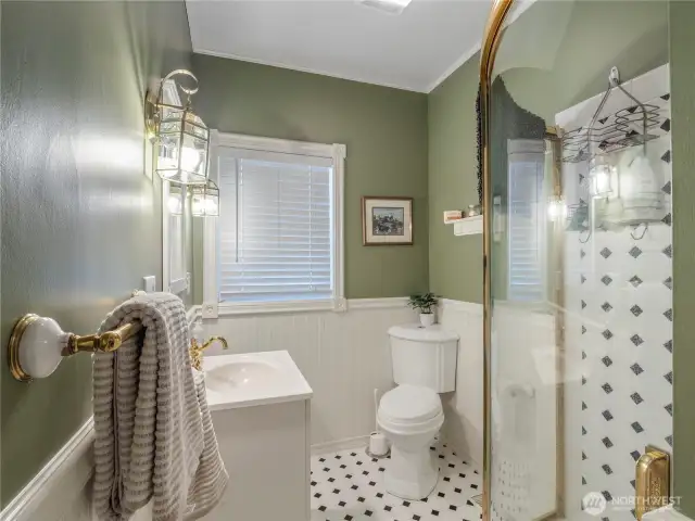 Main floor guest bathroom with classic black and white tile, bead board, and brass accented lighting and hardware.