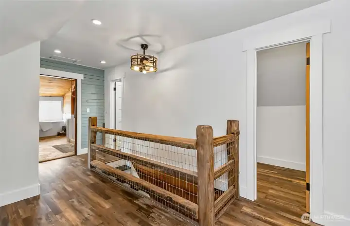 At the top of the stairs is the hallway between the primary bath & bedroom.  Love the creative wood staircase!