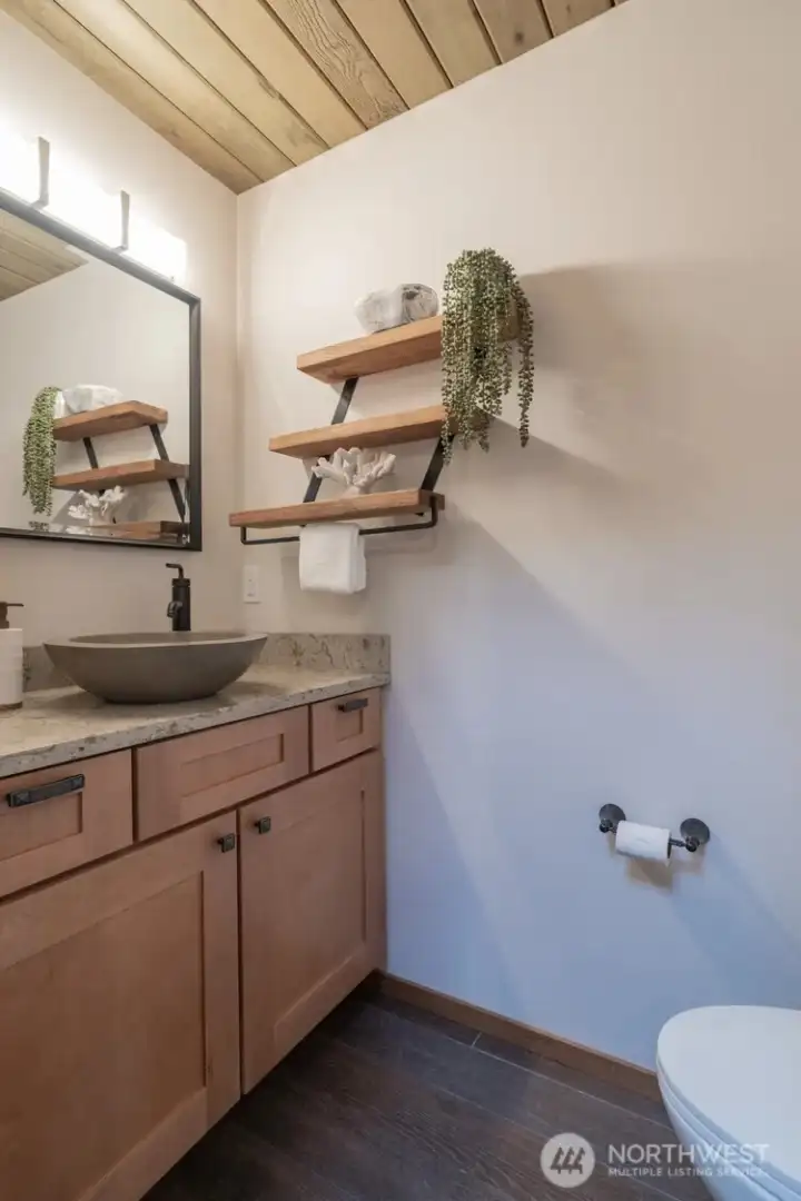 The powder bath off the entry for guests with wood looking tile floors and solid countertops. The powder bath off the entry for guests with wood looking tile floors and solid countertops.