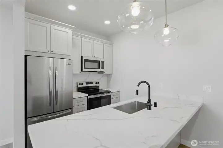 Modern kitchen with quartz countertops, stainless appliances, and island seating