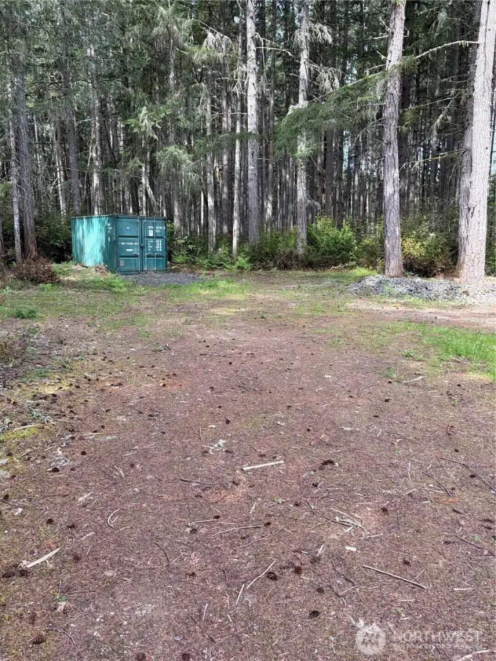 Shipping container provide secure on-site storage. Tucked among the trees at the edge of the cleared area.